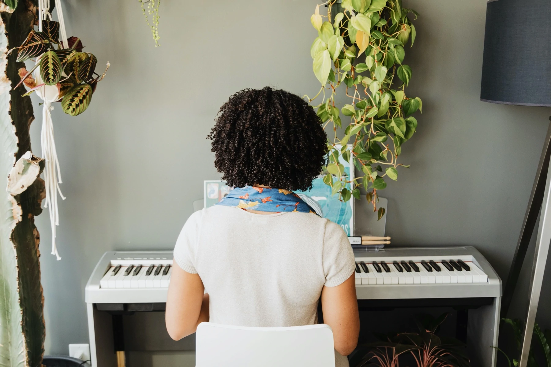 Una donna siede al pianoforte con la schiena girata verso la telecamera