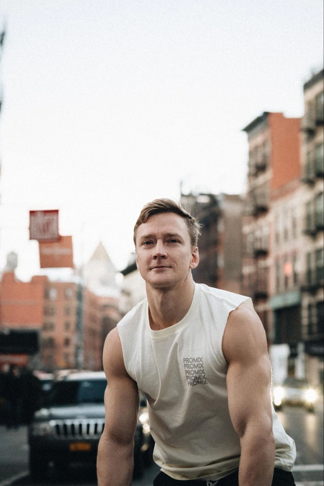 Un modelo masculino con una ciudad como telón de fondo con una camiseta de entrenamiento de Promix.