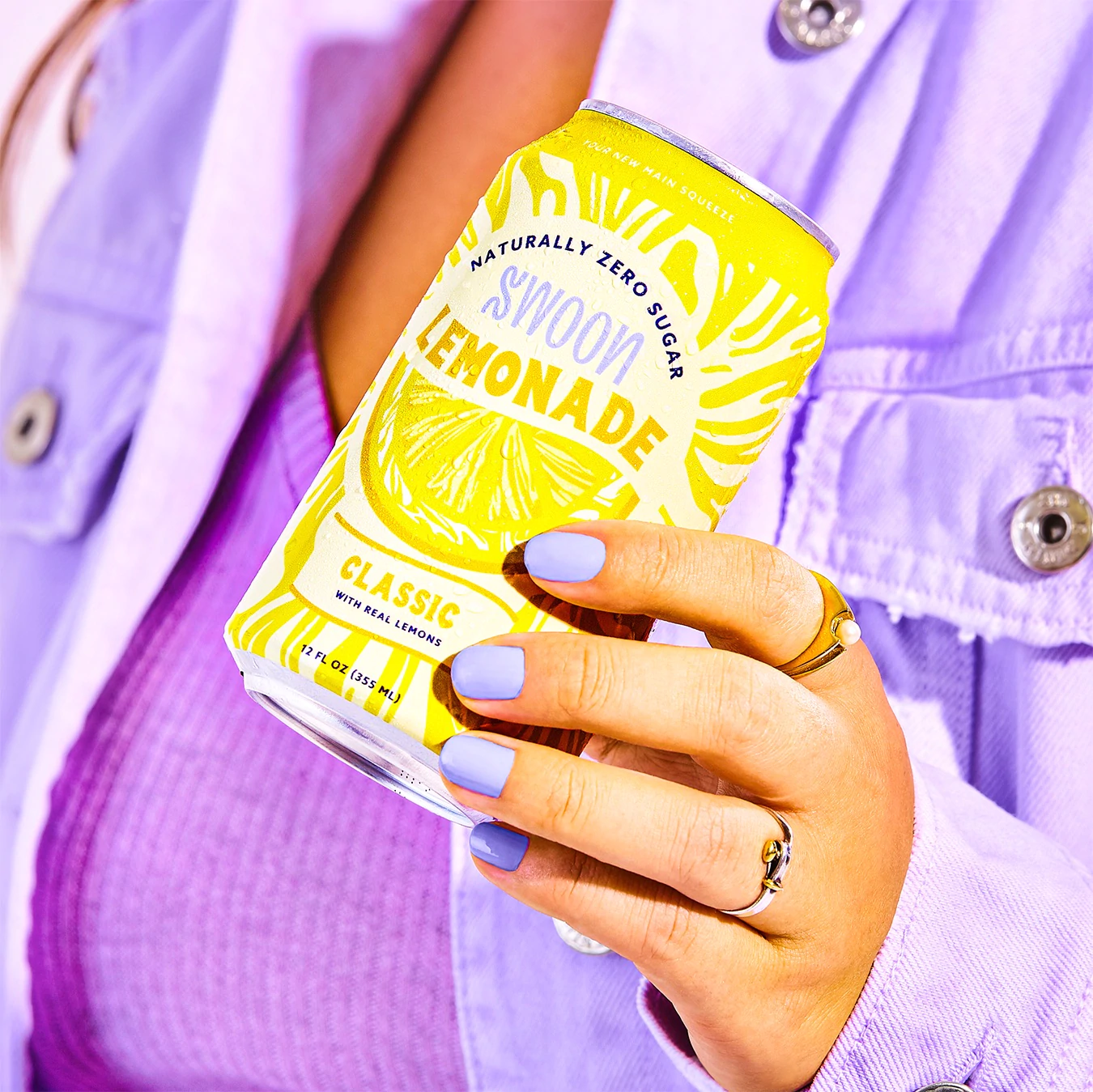 عصير ليمونادة كلاسيكي من Swoon يحمله نموذج يرتدي ملابس أرجوانية.