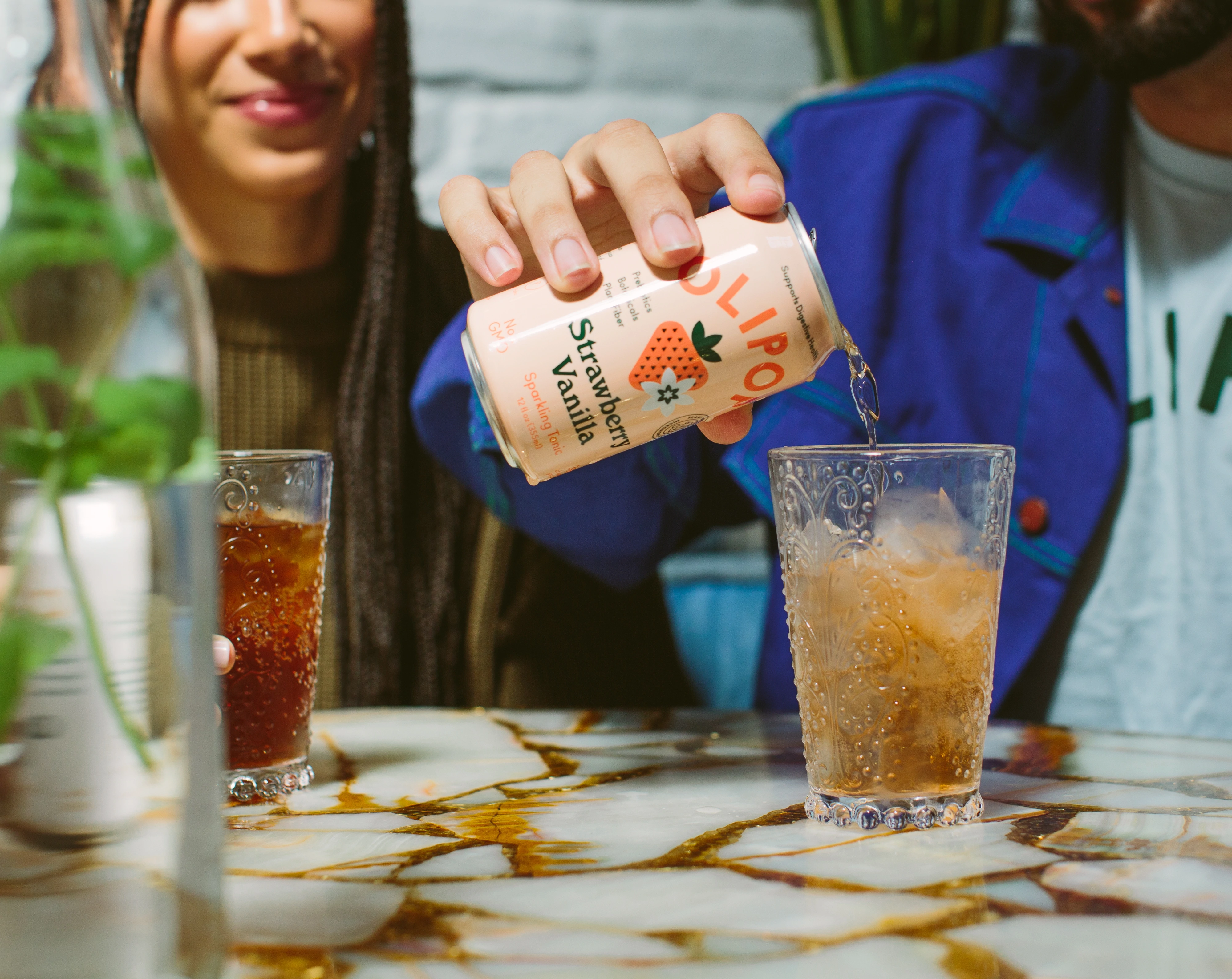 Un bărbat care toarnă o cutie de Olipop cu căpșuni și vanilie într-un pahar