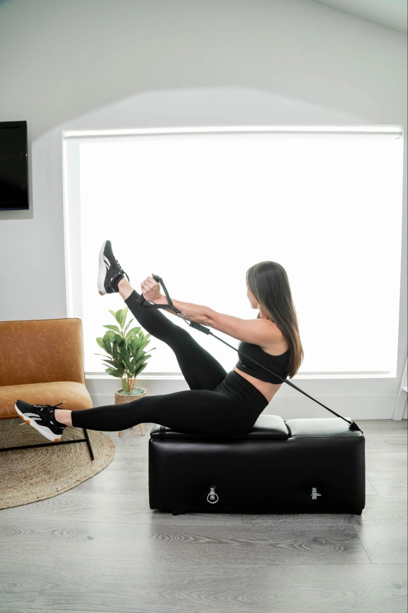 Ein Model benutzt eine Trainingsbank von Zeno Gym neben einer Couch in einem Wohnzimmer.