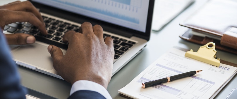 Bărbat care scrie pe laptop cu Factură lângă el