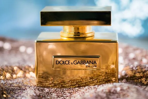 photo de beauté du produit d'une bouteille brillante de Dolce & Gabbana "the one" posée sur un lit de tissu à paillettes