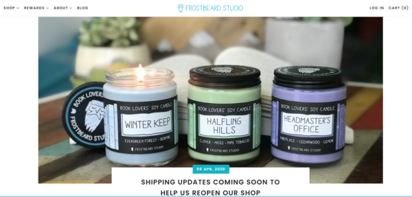 Zestaw do fotografii produktowej - trzy świece słojowe w różnych kolorach umieszczone razem ze świecą po lewej zapaloną i tłem otwartej książki i roślin doniczkowych