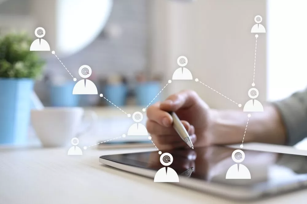 Mão usando um tablet com um gráfico de sobreposição de pessoas conectadas