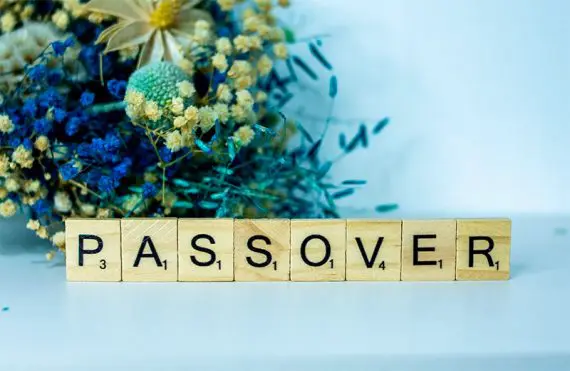 앞면에 "유월절"이라고 쓰여 있는 스크래블 글자가 있는 꽃 사진. Photo of flowers with Scrabble letters in front reading" Passover."