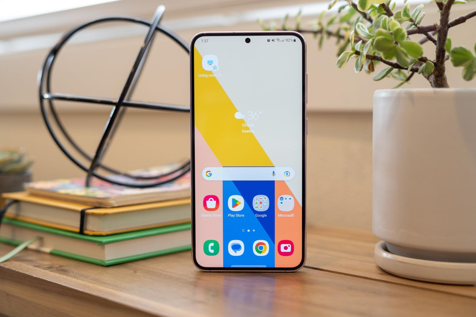 Samsung Galaxy S23 Plus stând în picioare pe o masă, arătând ecranul de pornire și tapetul colorat.